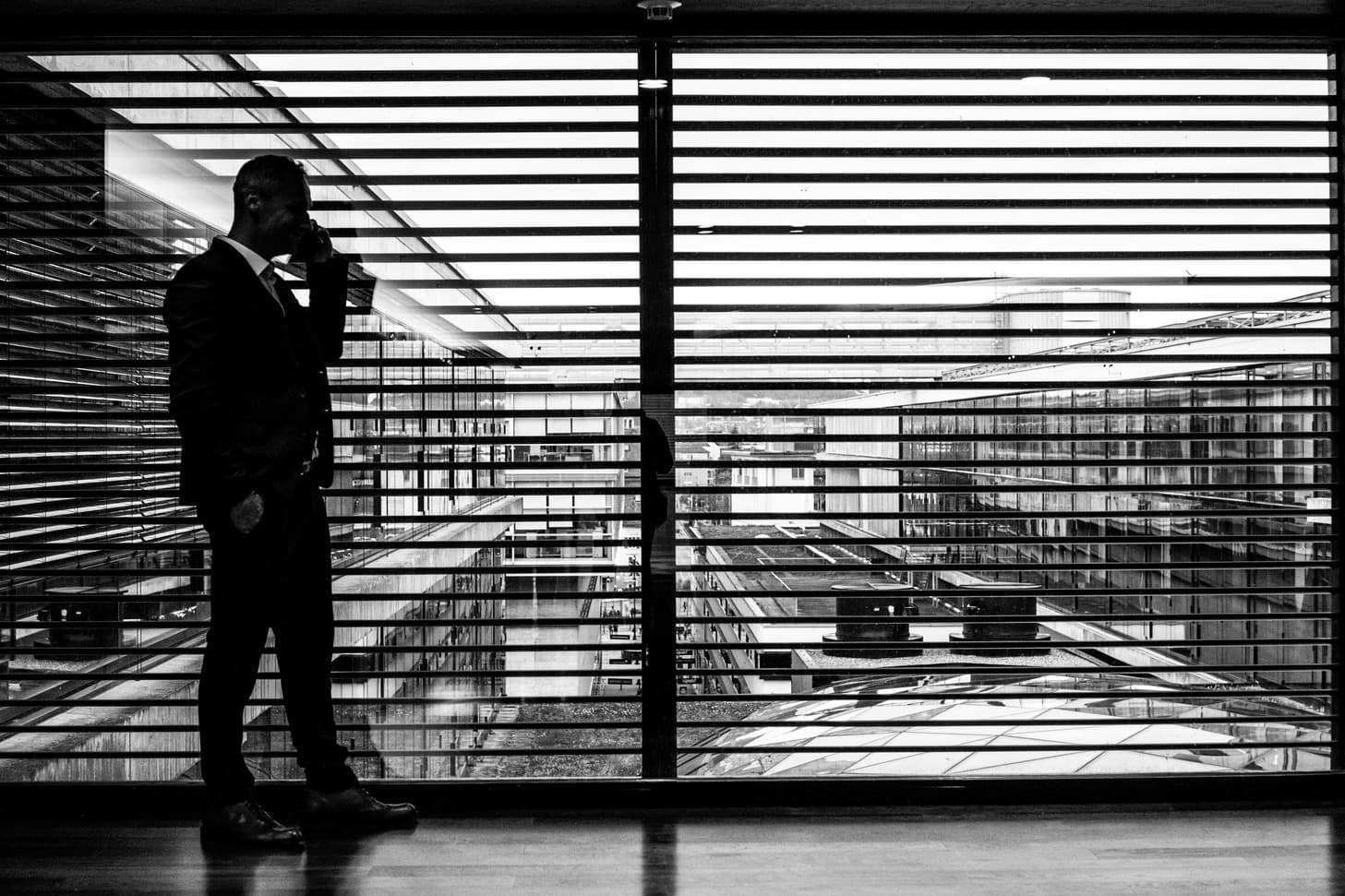 Suited man walking in a dark business setting using a mobile phone